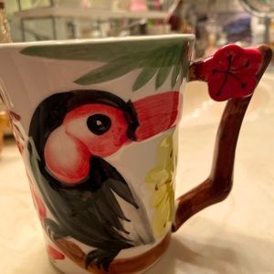 a cup with a bird Tukan and a flower.